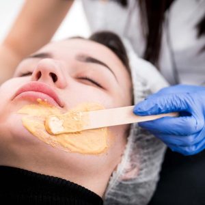 Beautician applying facial mask at cosmetic clinic, cosmetology treatment skincare face