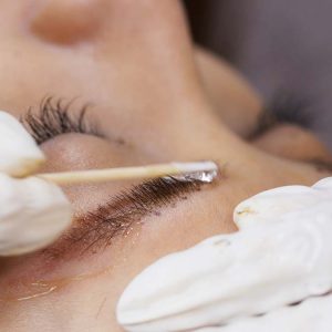 Beautician hands doing eyebrow microblading with ink needle
