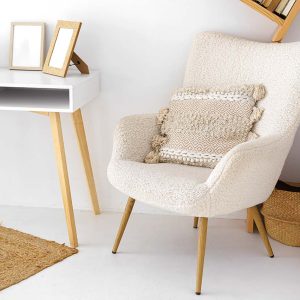 A soft, textured white plush chair with decorative pillow bright light room. Natural elements like jute rug and woven basket add warmth to minimalist decor of living room. Home decor, interior design