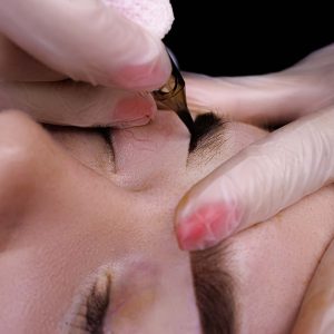 Macro shot of permanent eyebrow makeup procedure, the master performs a tattoo on the model's eyebrows.
