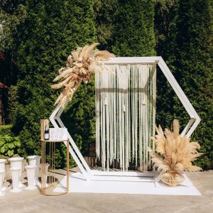 Wedding ceremony in the garden for the bride and groom. The arch is made of fresh flowers and dead wood, reeds. Outdoor wedding ceremony. High quality photo