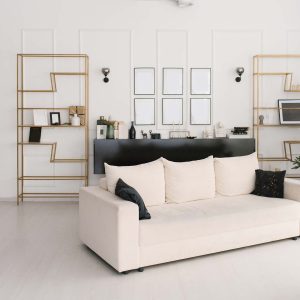 White and black interior of the living room with a sofa with pillows and a wardrobe a rack and mockups photo frames or illustrations on the wall